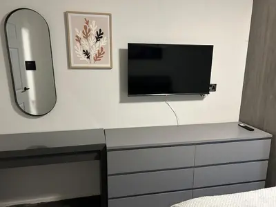 a bedroom with a dresser with a tv and a mirror at Spacious 2 bedroom apartment, entire place in Greenock