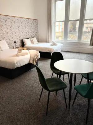 a room with two beds and a table and chairs at Piccolo in Glasgow