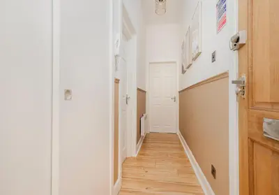 a hallway with white walls and a wooden door at Argyl - Grassmarket Apartments in Edinburgh