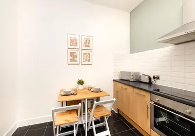a kitchen with a small wooden table and chairs at Argyl - Grassmarket Apartments in Edinburgh