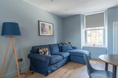 a living room with a blue couch and a table at Prime Stay Apartments in Paisley