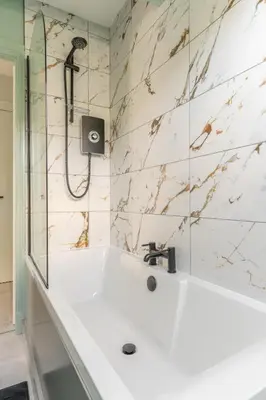 a bathroom with a shower and a white tub at Prime Stay Apartments in Paisley