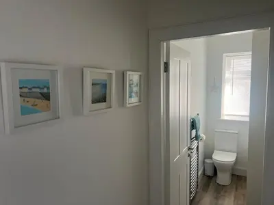 a bathroom with a toilet and three pictures on the wall at Greenwood South - Luxury beachfront home with log burner in Kames
