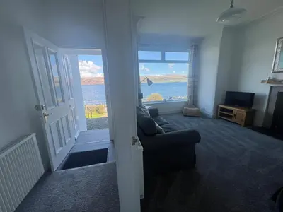 a living room with a couch and a view of the ocean at Greenwood South - Luxury beachfront home with log burner in Kames