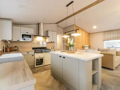 a large kitchen with white cabinets and a kitchen island at Debonair Lodge in Newton Stewart