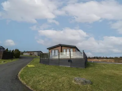 a small house sitting on the side of a road at Debonair Lodge in Newton Stewart