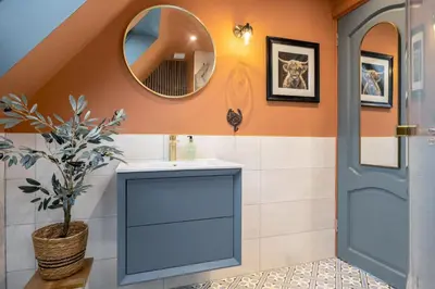 a bathroom with a blue vanity and a mirror at The Unique Cathedral Hideaway in Stirling