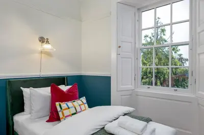a room with a window and a couch with pillows at Charming and Cosy Getaway in Cambusbarron