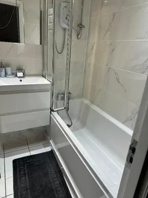 a white bathroom with a shower and a sink at The City Glasgow in Glasgow