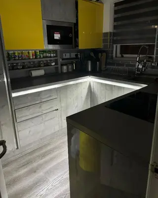 a kitchen with a black counter top and yellow cabinets at The City Glasgow in Glasgow