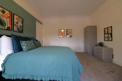 a bedroom with a blue bed and a dresser at Signature - St James House in Abbotsinch