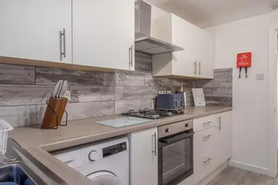 a kitchen with white cabinets and a stove top oven at Boswell House - Modern 3 Bed House East Kilbride Close to Motorway in East Kilbride