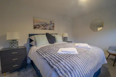 a bedroom with a bed with a blue comforter at Boswell House - Modern 3 Bed House East Kilbride Close to Motorway in East Kilbride