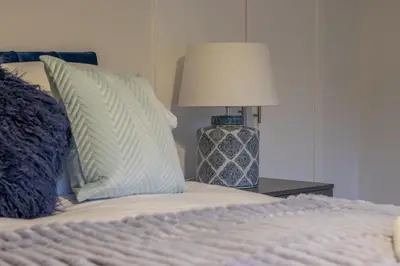 a bed with pillows and a lamp on a table at Boswell House - Modern 3 Bed House East Kilbride Close to Motorway in East Kilbride
