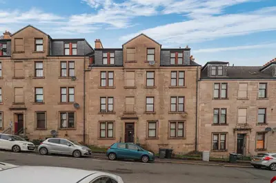 a large brick building with cars parked in front of it at Sonas Apartment in Greenock
