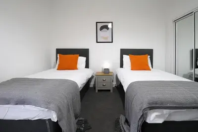 two beds sitting next to each other in a room at Sonas Apartment in Greenock