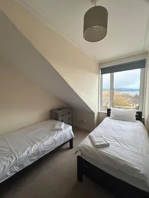 a bedroom with two beds and a large window at The Bay View Apartment in Gourock