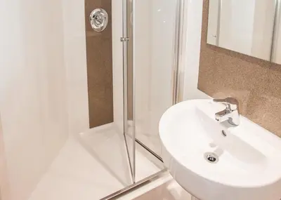 a white bathroom with a shower and a sink at Willow Court in Stirling