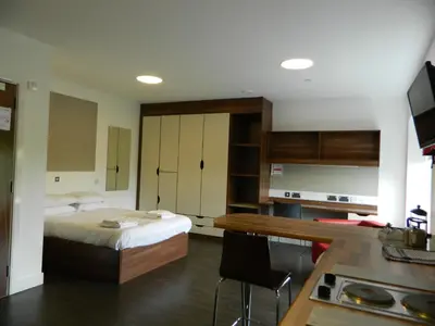 a bedroom with a bed and a desk and a kitchen at Willow Court in Stirling