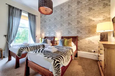 two beds in a bedroom with zebra print walls at Maya's Holiday Homes in Glasgow