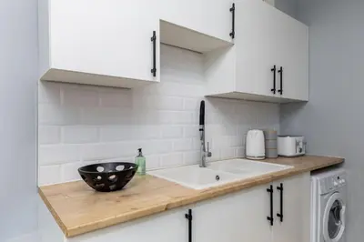 a kitchen counter with a sink and a washing machine at Castle Esplanade Apartment in Stirling