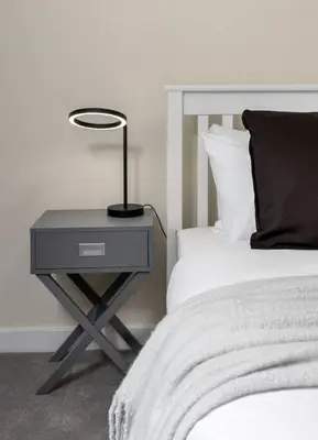 a bedside table with a lamp on it next to a bed at Castle Esplanade Apartment in Stirling