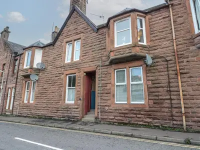 a brick house with a red door on a street at Lismore in Crieff
