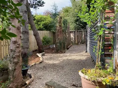a garden with a fence and a tree in a yard at The Old Shed in Benderloch