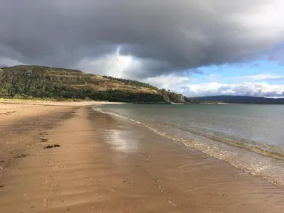 a view of a beach with the ocean and mountains at The Old Shed in Benderloch