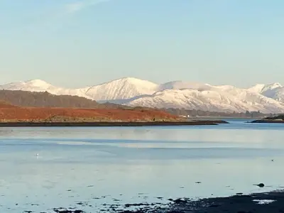 a large body of water with snowy mountains in the background at The Old Shed in Benderloch