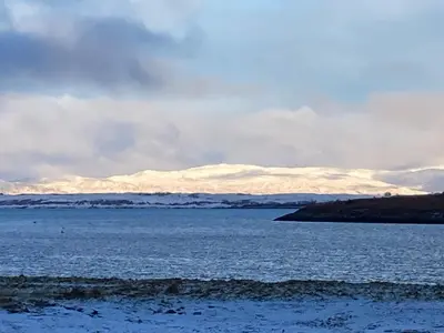 a large body of water with snow covered mountains in the background at The Old Shed in Benderloch