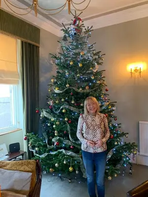a woman standing in front of a christmas tree at Foresters 4 Bedroom Apartment in Cambusbarron