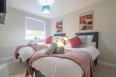 a bedroom with two beds with red and white blankets at Hawick Apartment- 2-Bed in Coatbridge, Mins from Motorway to Glasgow in Old Monkland