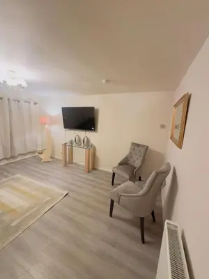 a living room with a chair and a flat screen tv at Modern & Cosy 3 Bedroom Inverkeithing home- Ideal for Edinburgh Dunfermline & St Andrews with Free Parking in Inverkeithing