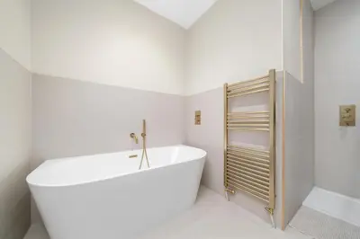 a white bathroom with a tub and a shower at Paisley Road Courtyard in Glasgow