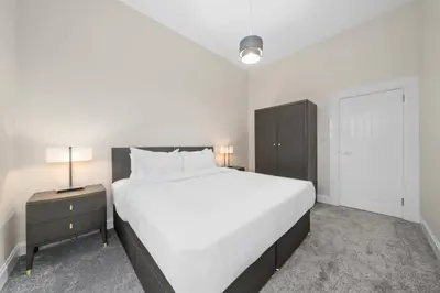 a white bedroom with a large bed and a nightstand at Paisley Road Courtyard in Glasgow