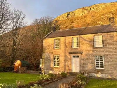 an old brick house with a hill in the background at The Coach House in Stirling