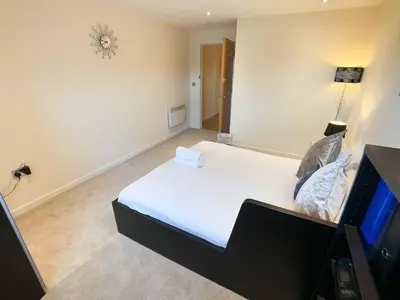 a bedroom with a white bed and a television at Glasgow 2bd near Hydro SECC City Centre Great Location in Glasgow
