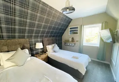 a bedroom with two beds and a window at Burlington Guest House in Whiting Bay
