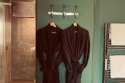 twouits hanging on a rack in a bathroom at Loch Lomond Hideaways- Luxury Cabins with Jacuzzi Hot Tubs for Two in Drymen
