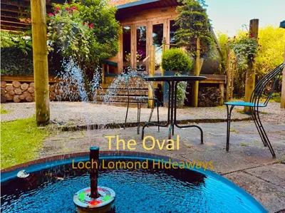 a pool with a fountain in front of a house at Loch Lomond Hideaways- Luxury Cabins with Jacuzzi Hot Tubs for Two in Drymen