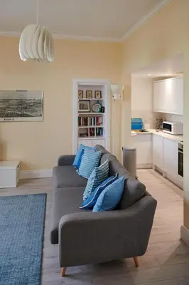 a living room with a gray couch with blue pillows at Swan Cove Apartment Gourock in Gourock