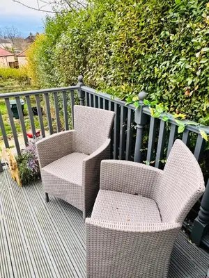 two wicker chairs and a chair on a deck at Bright 3 bedroom house with private garden near Edinburgh - Woodside home in Rosyth