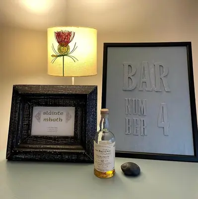 a bottle of whiskey next to a picture and a lamp at A 2 Bedroom flat in Culross home of Outlander in Culross