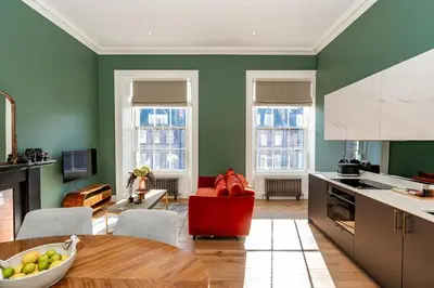 a kitchen with green walls and a red chair at Dragon Suites Luxury Apartments at 8 Albyn Place in Edinburgh