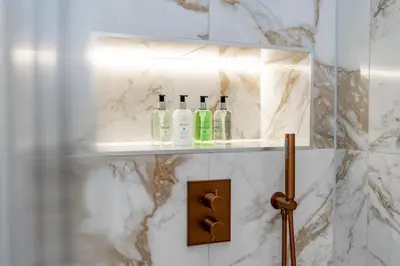 a bathroom with a shelf with bottles on it at Dragon Suites Luxury Apartments at 8 Albyn Place in Edinburgh