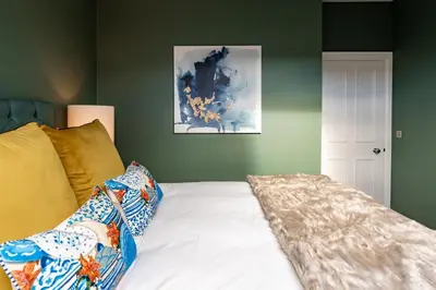 a bedroom with green walls and a bed with pillows at Dragon Suites Luxury Apartments at 8 Albyn Place in Edinburgh