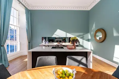a kitchen with blue walls and a table with a bowl of fruit at Dragon Suites Luxury Apartments at 8 Albyn Place in Edinburgh