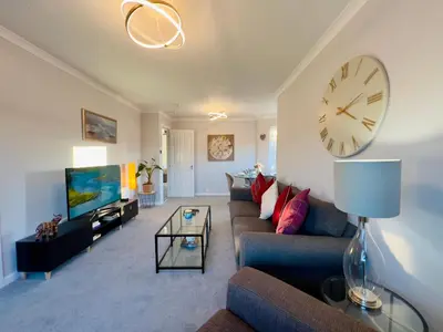 a living room with a couch and a clock on the wall at Chic & Cozy 2-Bed Flat in Glasgow - Free Parking in Glasgow