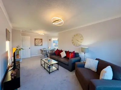 a living room with two couches and a clock on the wall at Chic & Cozy 2-Bed Flat in Glasgow - Free Parking in Glasgow